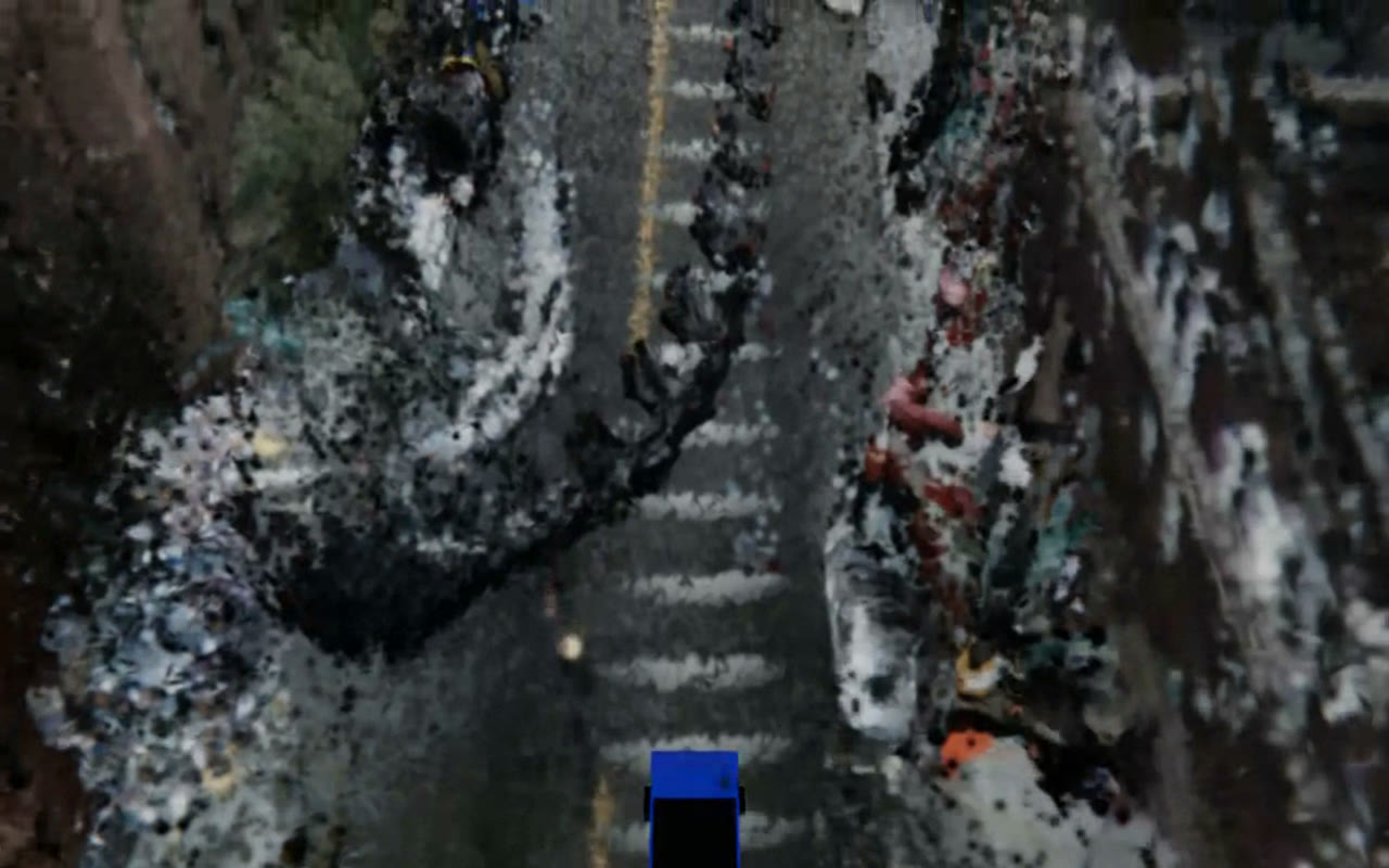 A clean top-down view of a street rendered as Gaussian splats: asphalt with a yellow centre line and crosswalk, parked cars rendered as colourful splat clusters, and curbside vegetation.